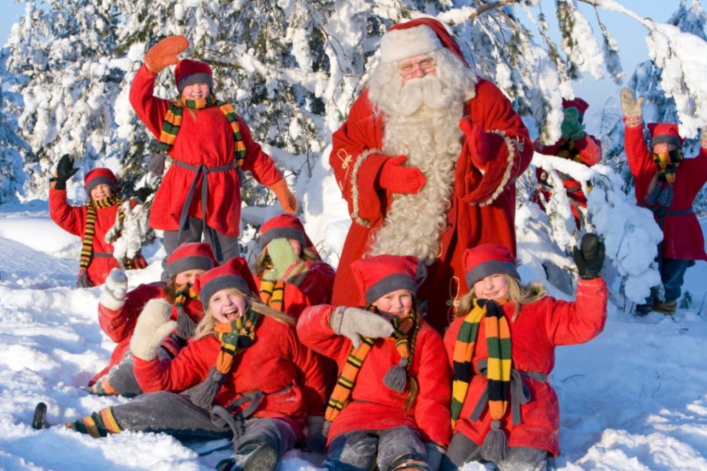 Family enjoying reindeer sleigh ride in Lapland 2027 with snow and Santa’s Hotel in the background.